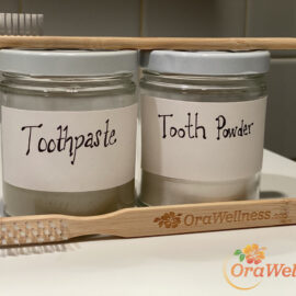 DIY Tooth Powder & Toothpaste Recipe - Picture of jars of homemade toothpaste and tooth powder with BrushEco toothbrushes and the Orawellness logo